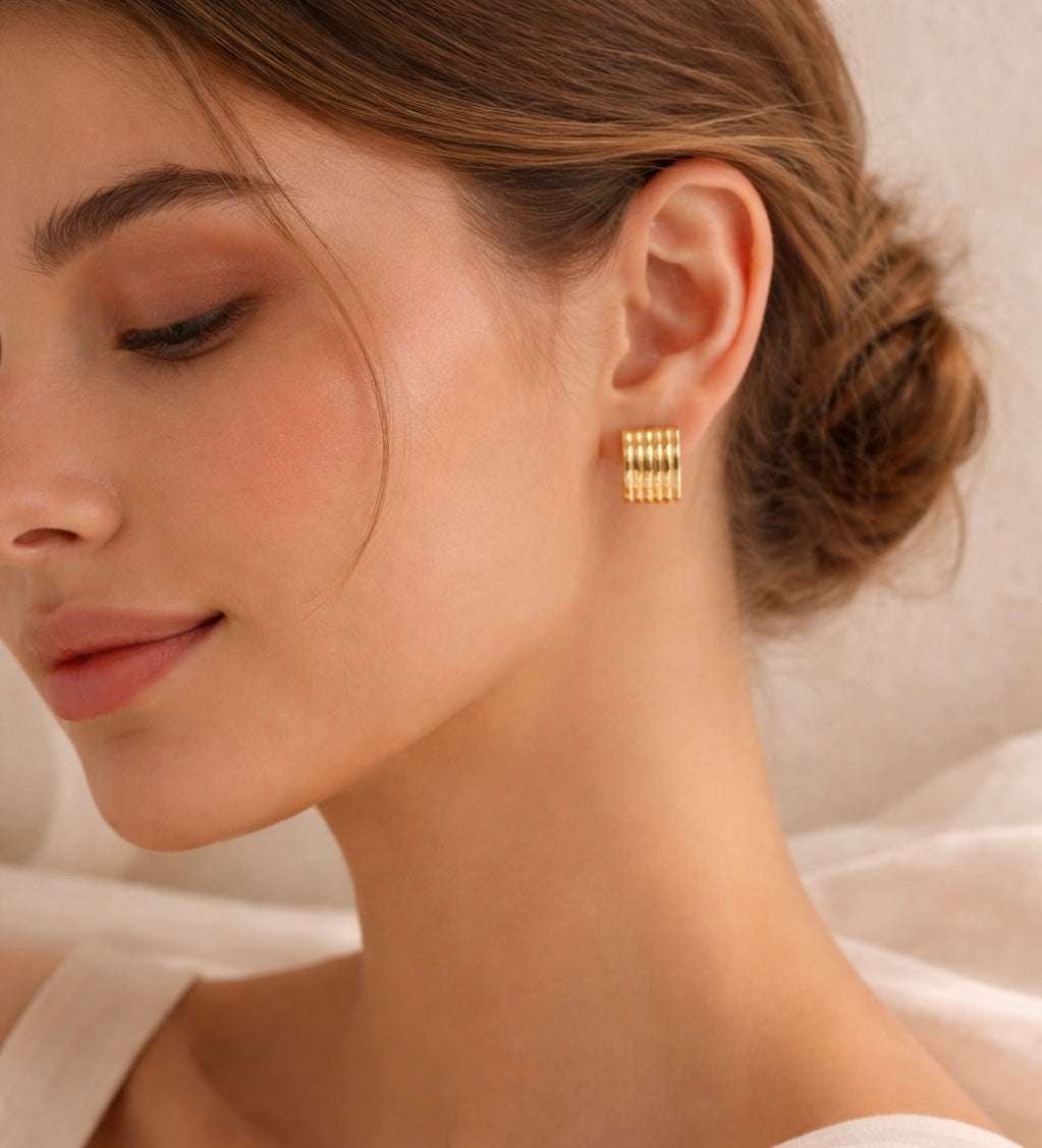Close-up of a woman wearing gold-plated ribbed hoop earrings, highlighting their elegant waterproof and tarnish-resistant design from the earrings collection.