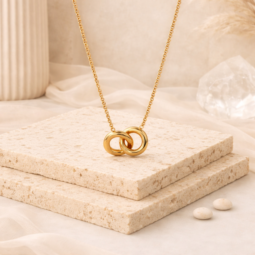 Elegant gold twin circles pendant necklace displayed on stacked textured stone slabs, styled in a neutral-toned setting from the Necklace collection.